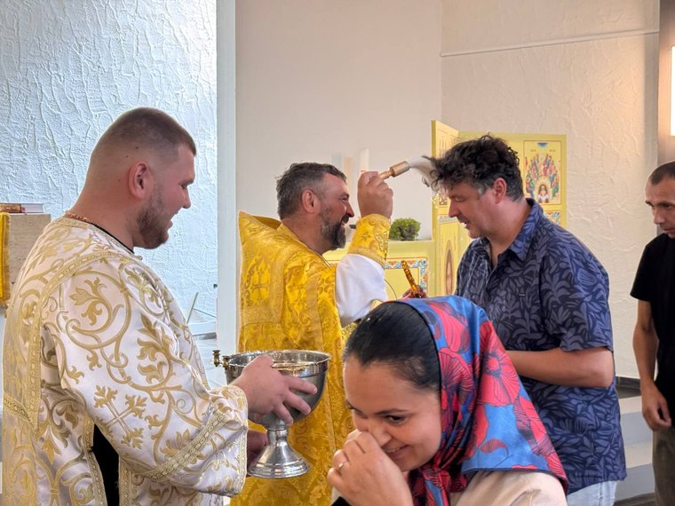 Священник кропить свяченою водою парафіян, прислужник тримає посудину